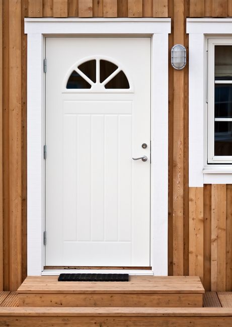 Białe drzwi zewnętrzne w drewnianym domu